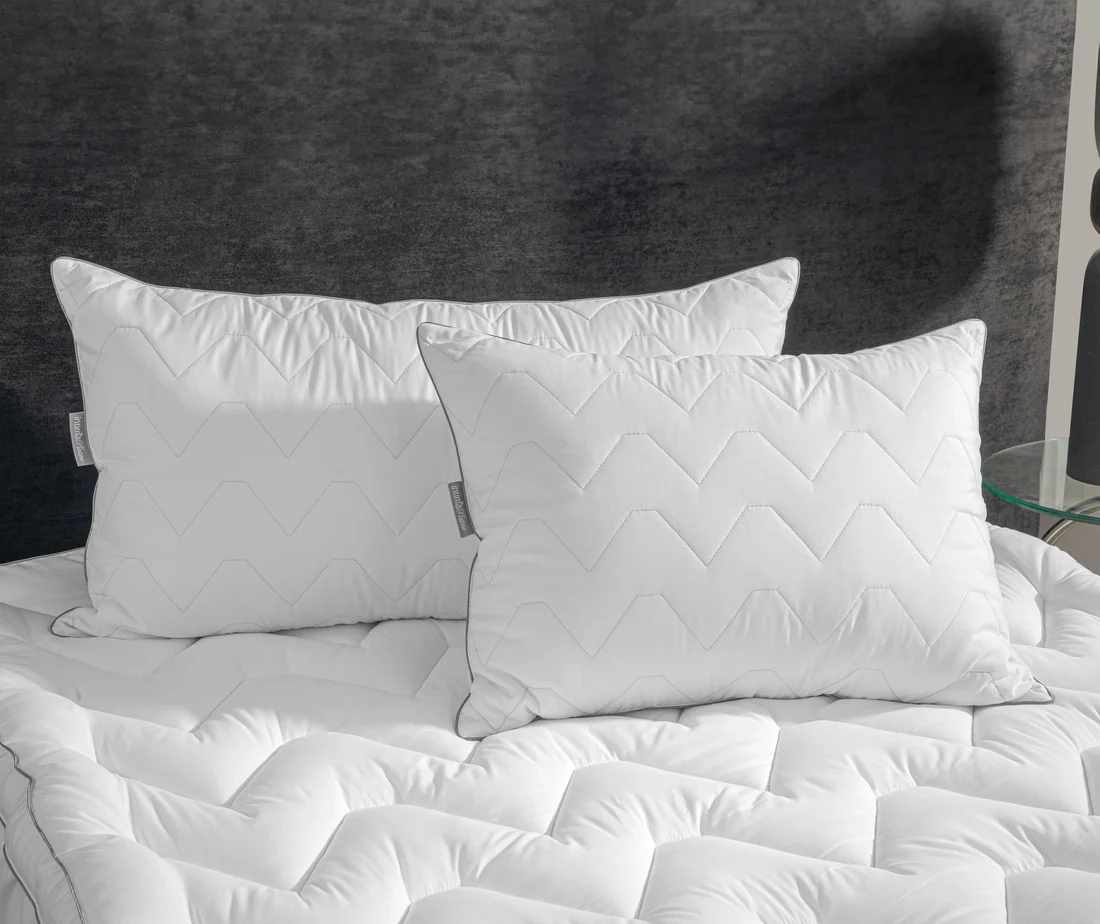 Almohadas blancas esponjosas apiladas en una cama